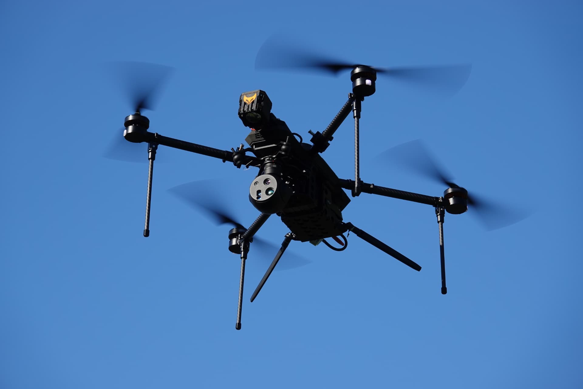 RECCE tactical quadcopter UAV silhouetted against a clear sky RECCE tactical quadcopter UAV silhouetted against a clear sky